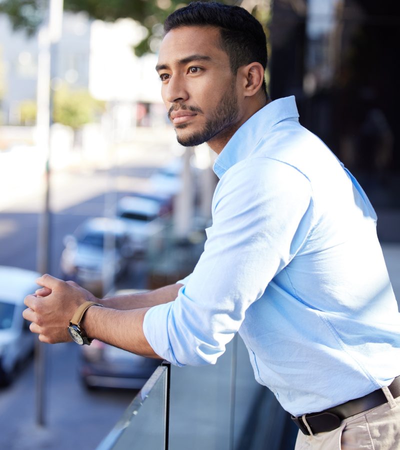 Shot of a young businessman looking thoughtful while standing on the balcony outside an office